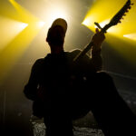Guitarist silhouette performing on stage with dramatic yellow lighting at Spark Arena.