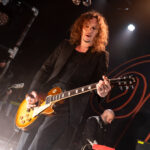 Darkness guitarist performing on stage at Powerstation, NZ, during February 2026 concert.