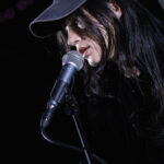 Harper Finn performing live at The 13th Floor, wearing a police-style cap with a crown emblem.