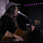 Harper Finn performing guitar and singing at The 13th Floor during a concert review.