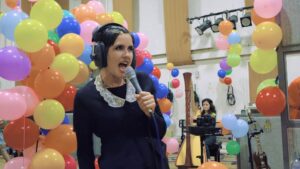 Princess Chelsea singing into a microphone surrounded by colorful balloons at Studio Two.